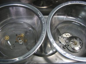 watch parts being transferred to another liquid